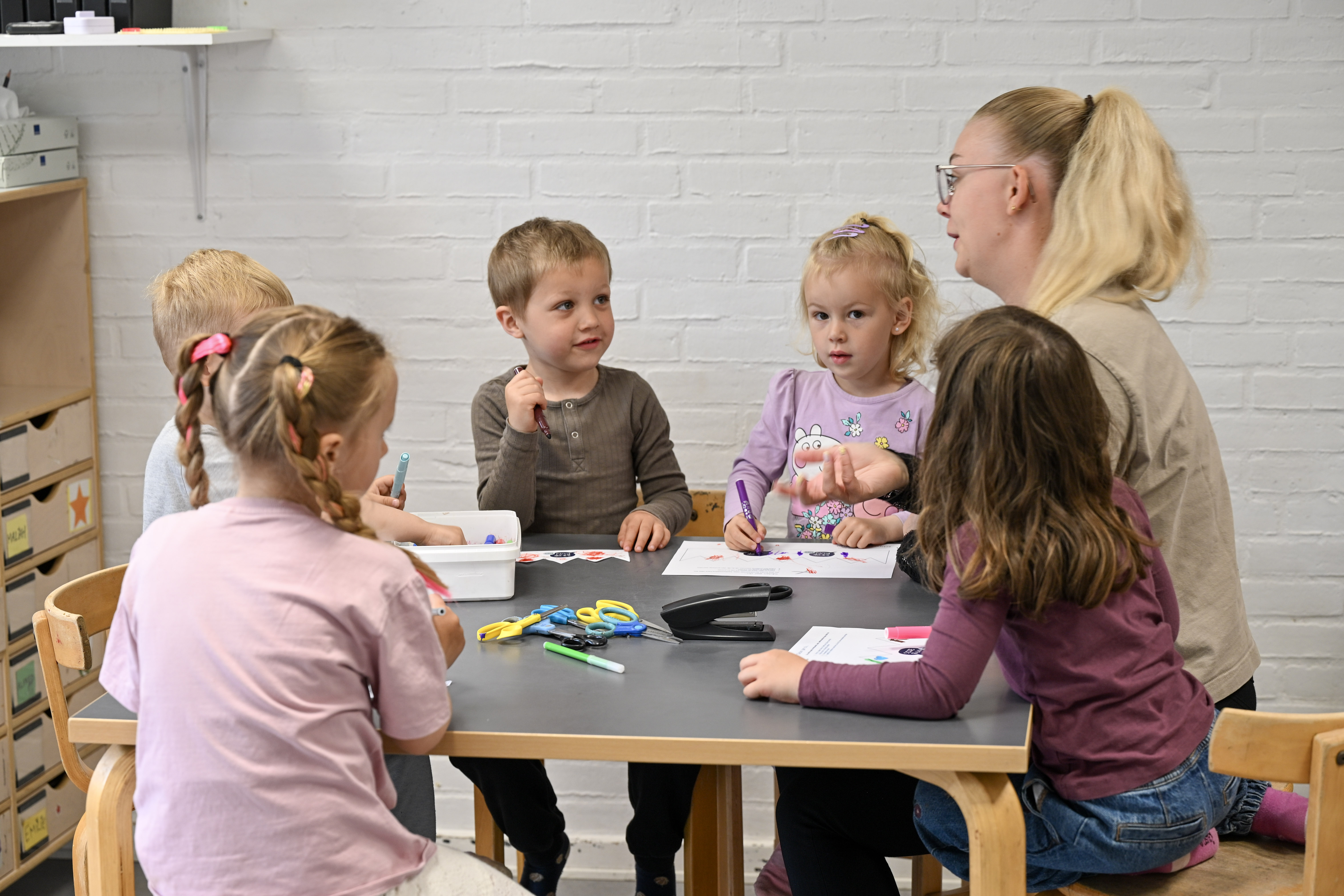 Pædagogmedhjælperen Julie og børn tegner ved bord