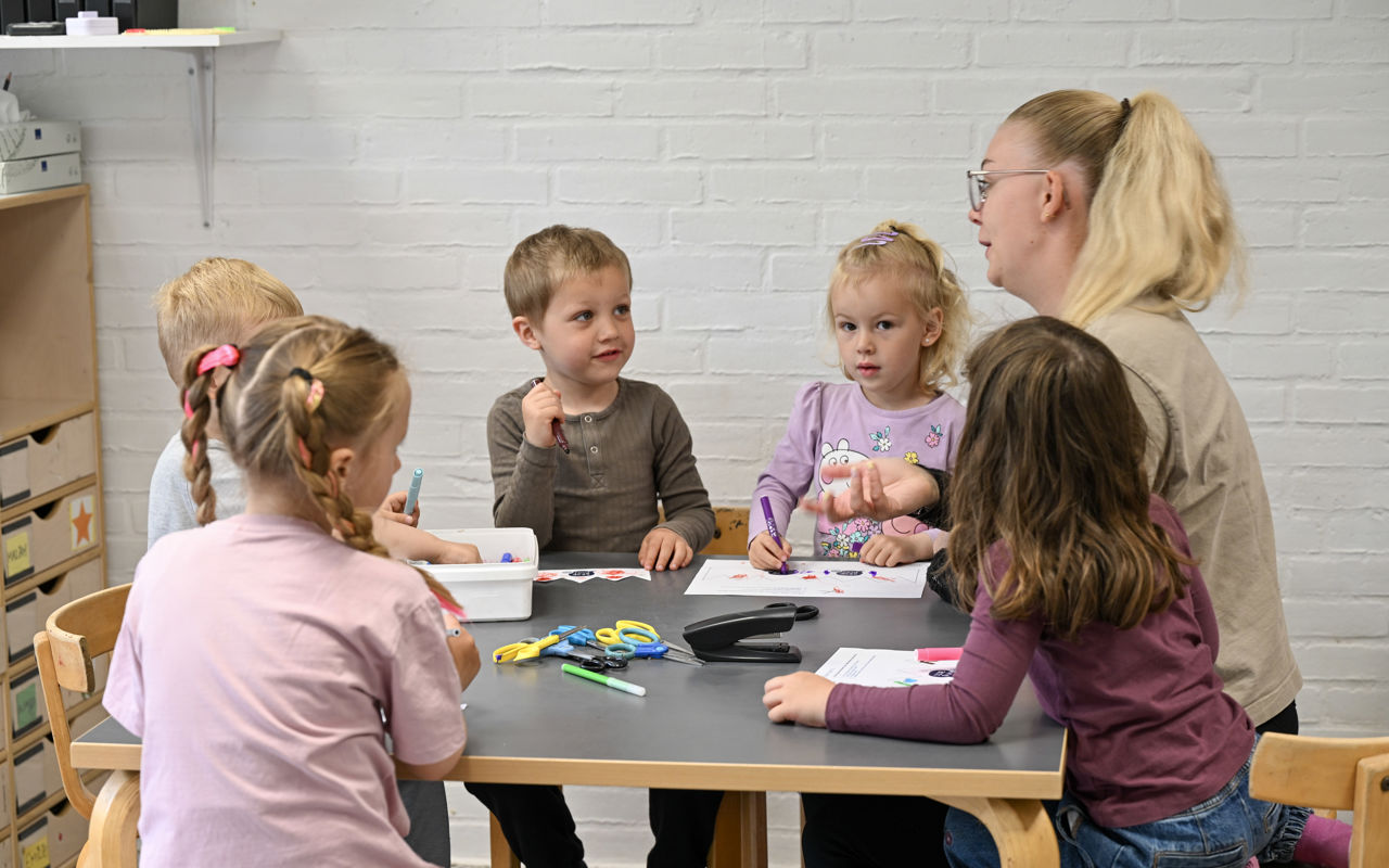 Pædagogmedhjælperen Julie og børn tegner ved bord