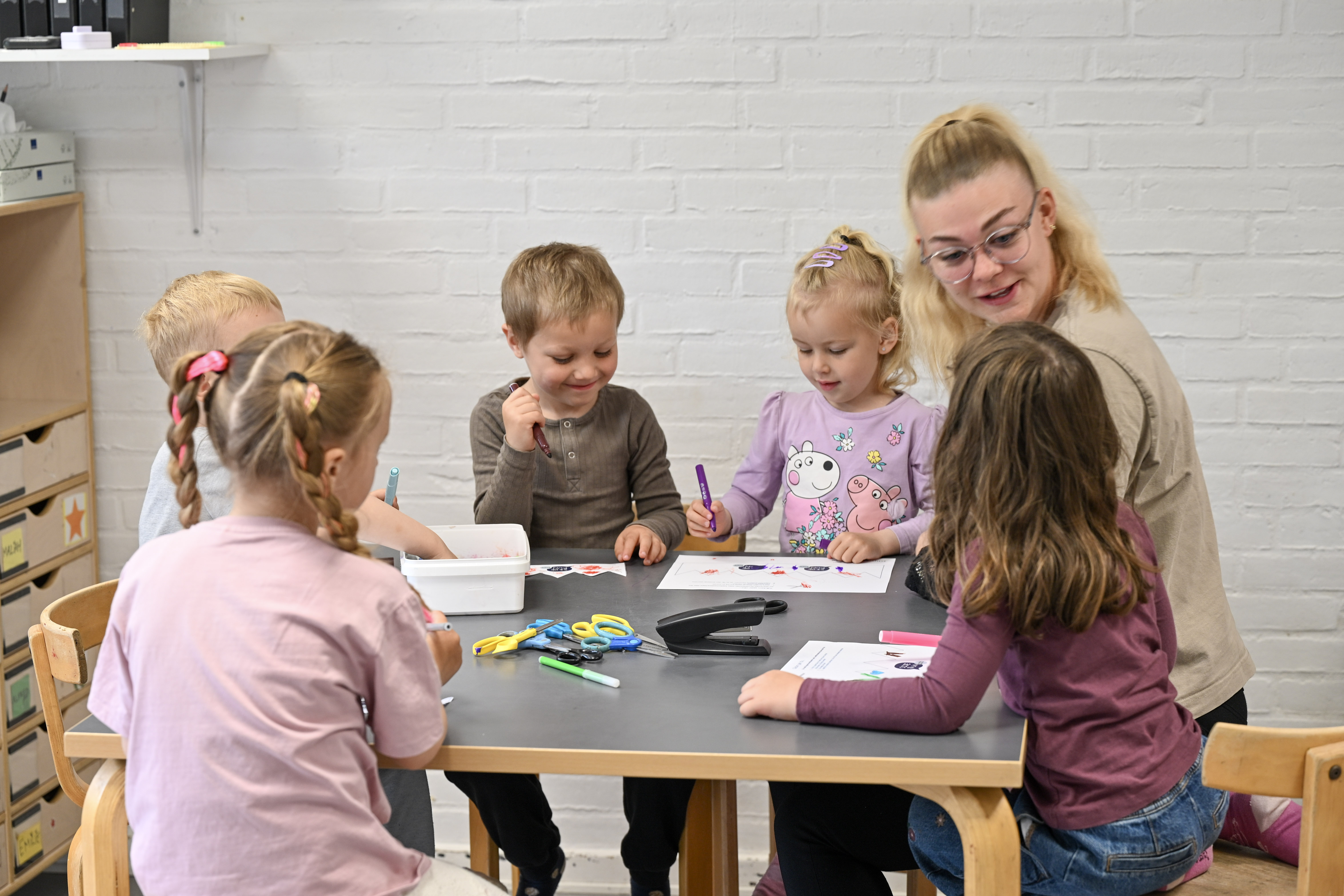 Pædagogmedhjælperen Julie og børn tegner ved bord