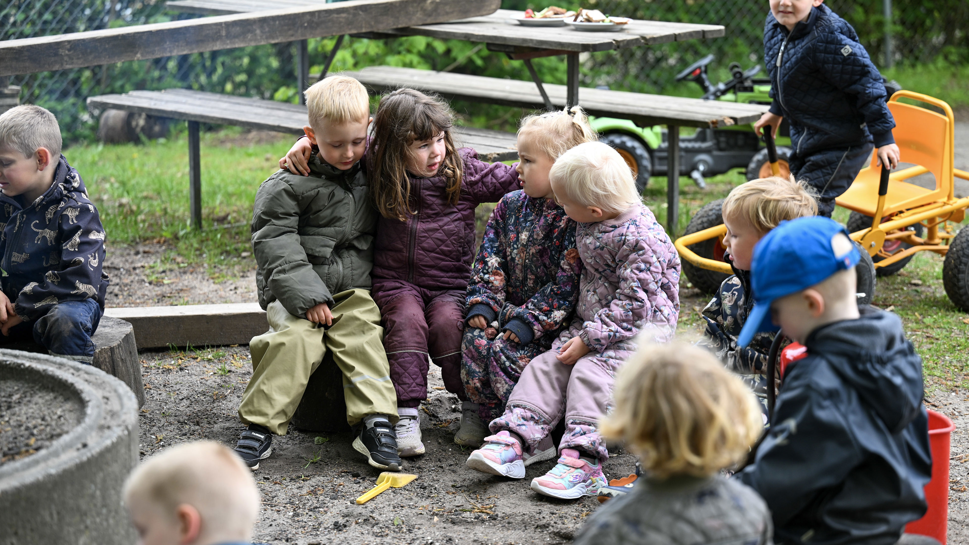 Børn sidder omkring bål