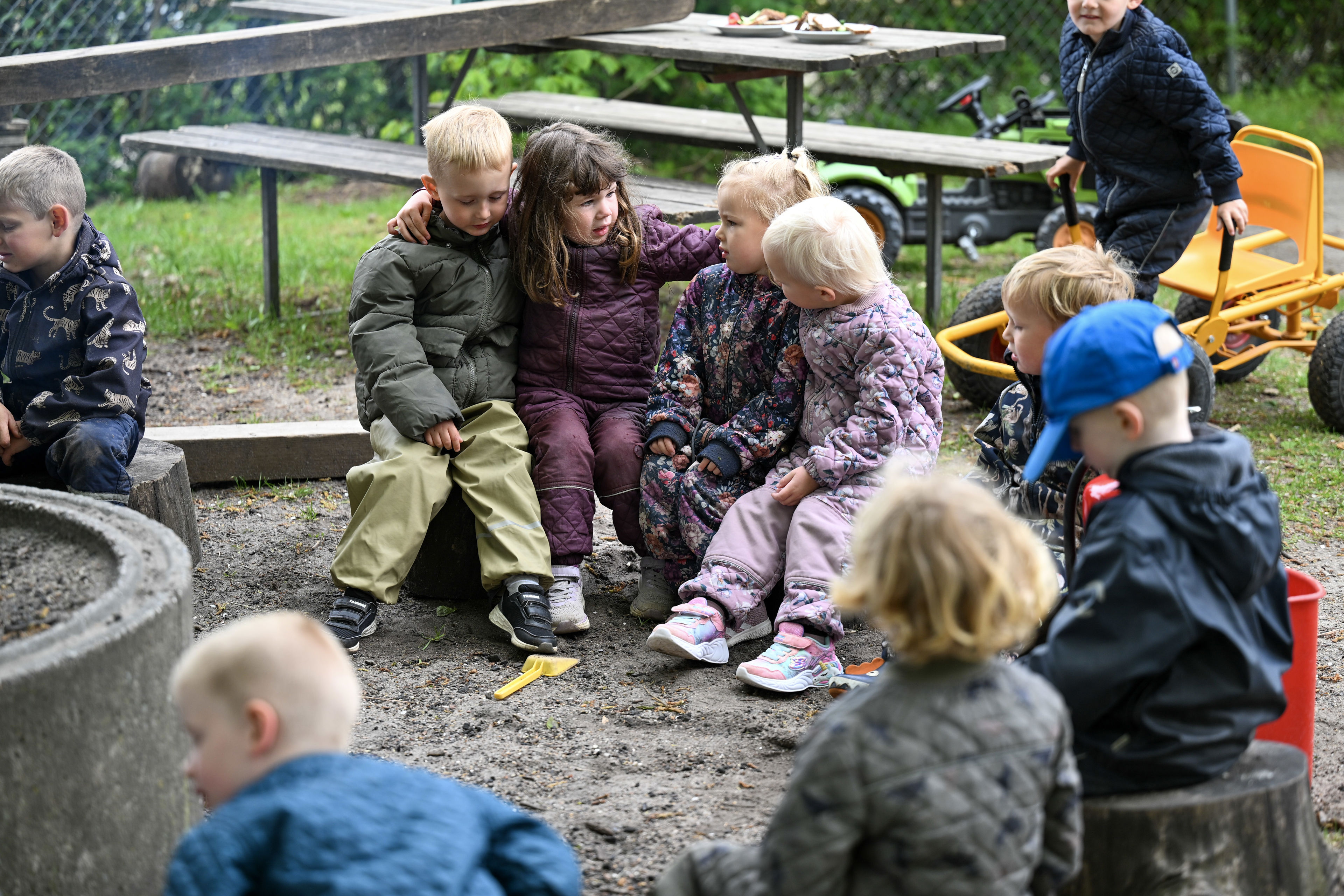 Børn sidder omkring bål