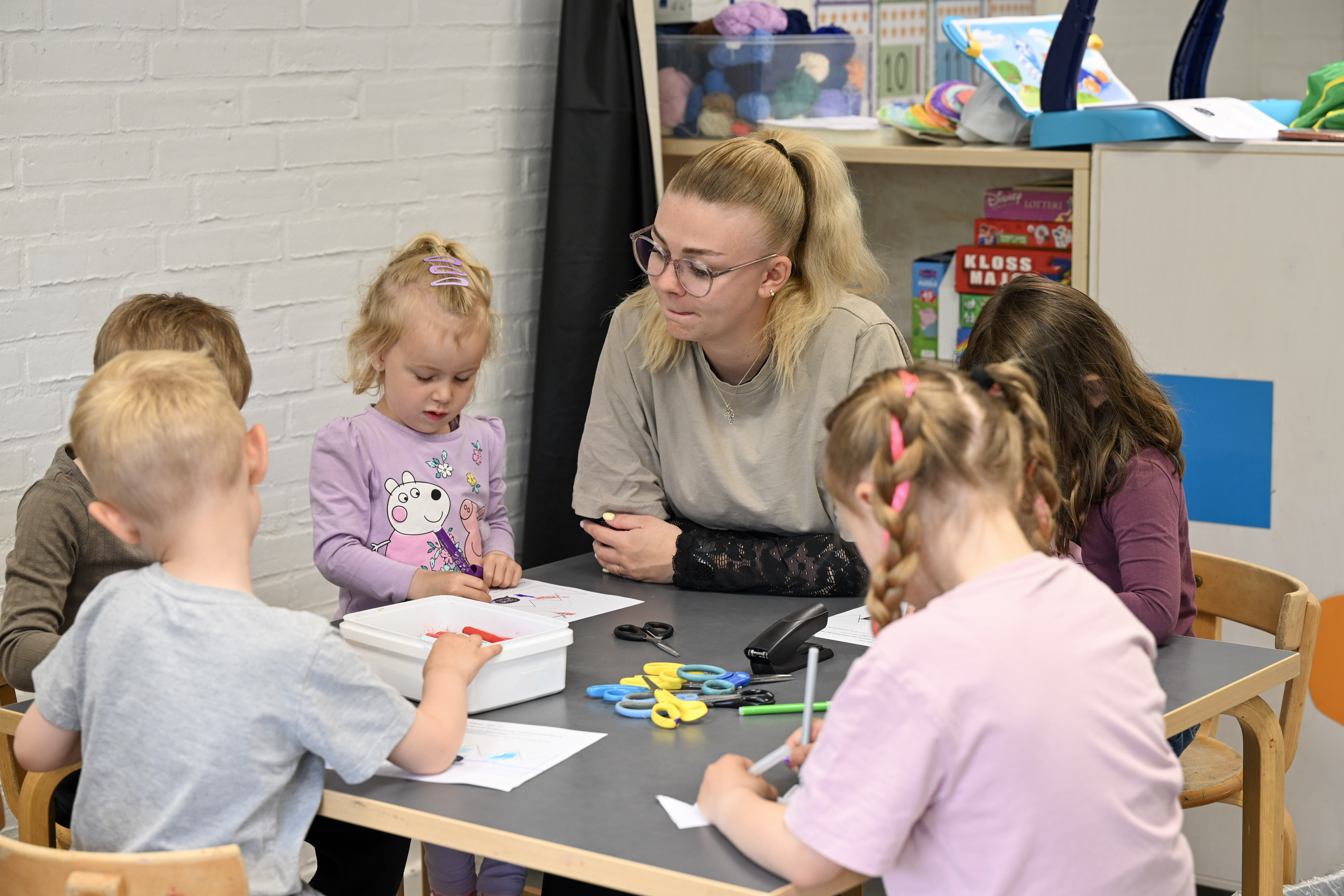 Pædagogmedhjælperen Julie og børn tegner ved bord